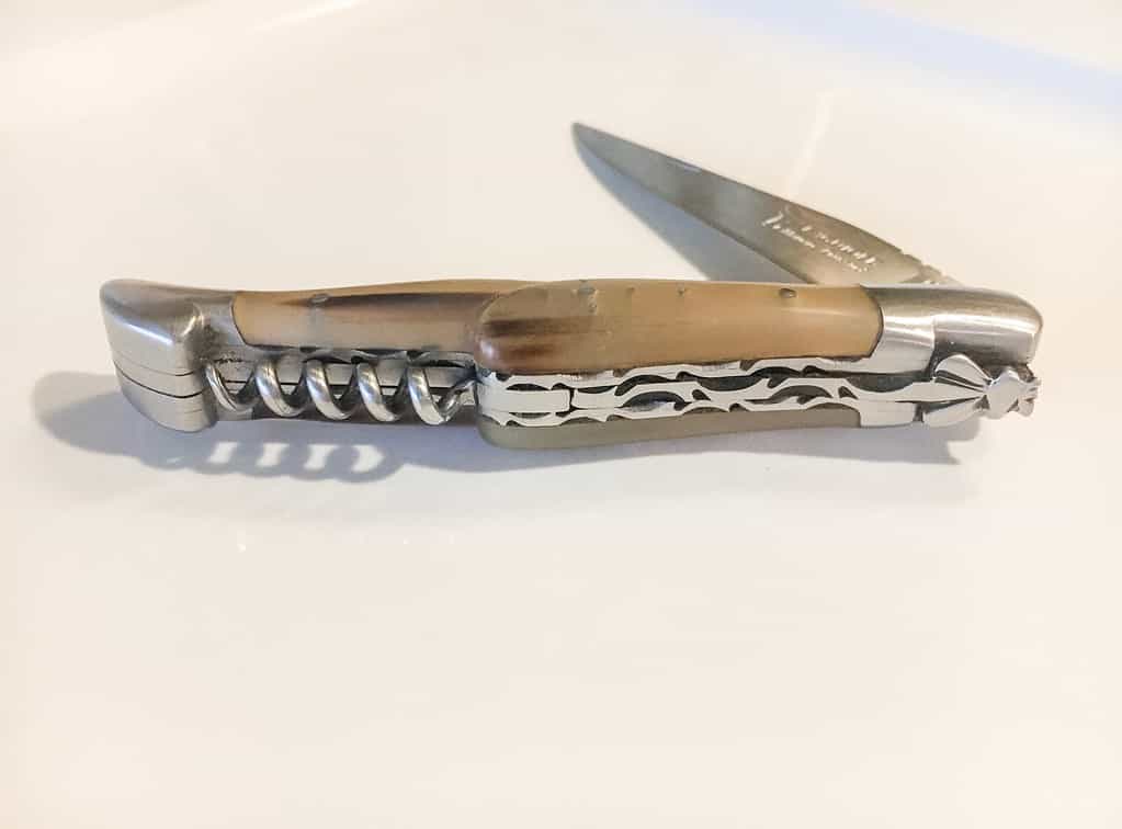 A side view of a half folded Laguiole pocket knife.