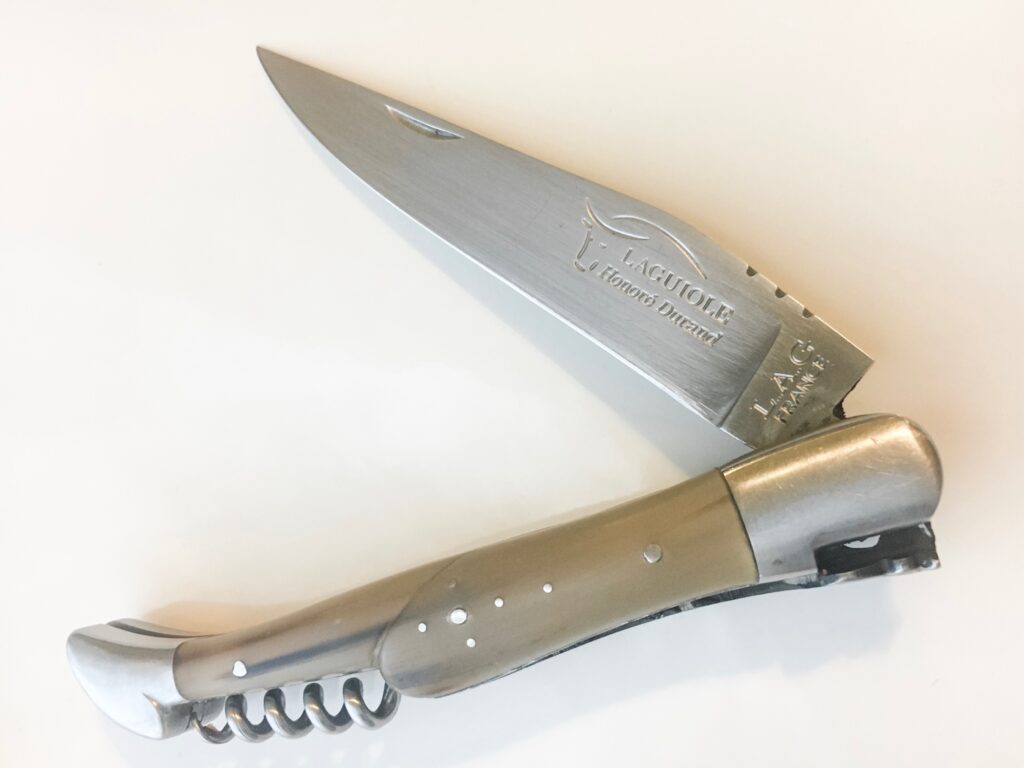 A half folded laguiole knife with a cross made from pins.