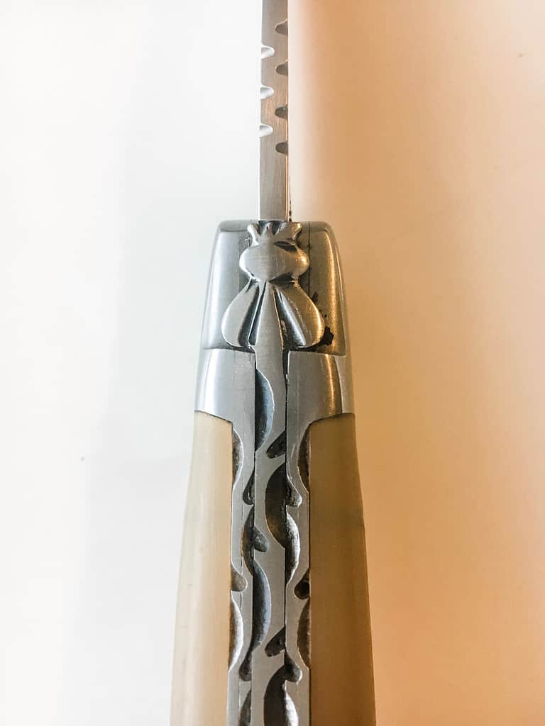 An up close picture of laguiole knife demonstrating the bee continuous with the spine.