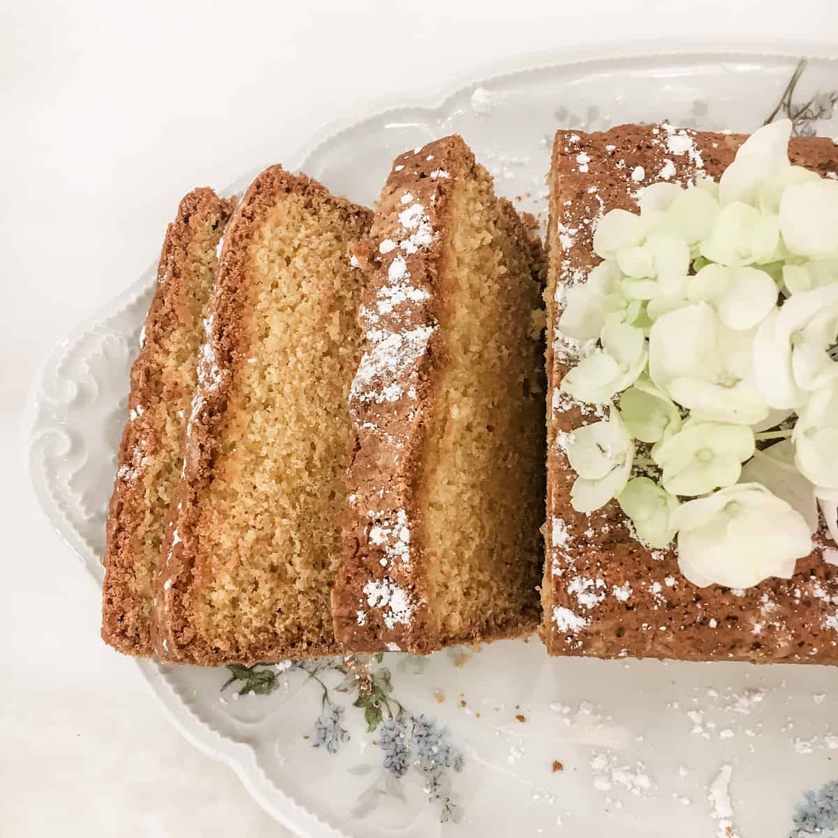 sliced French Madeleine cake on a platter with fresh flowers