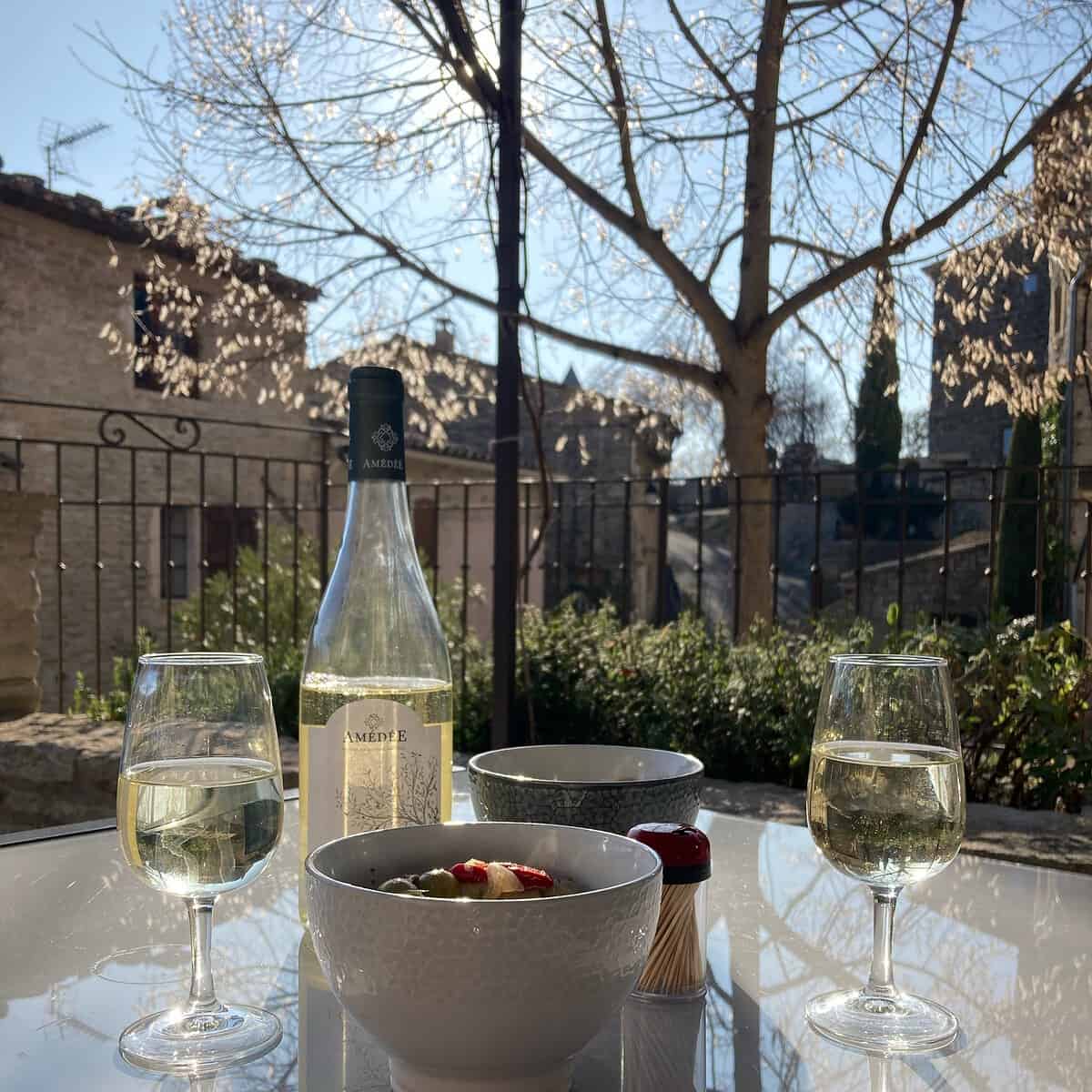 Wine glasses and wine bottle sitting on a table with Old Provencal buildings in the background