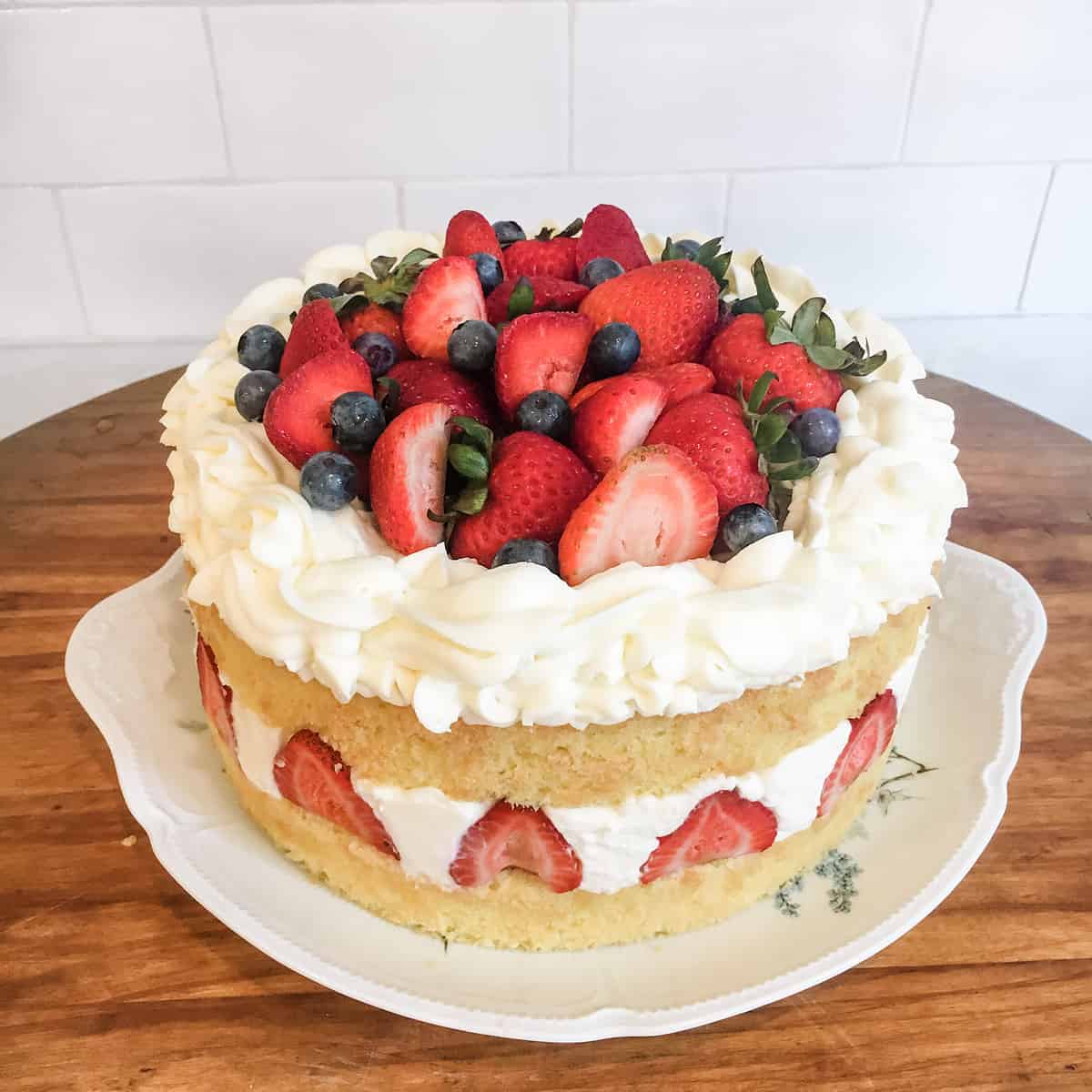 Blueberry and Strawberry Chantilly cake on a plate, sitting on a cutting board