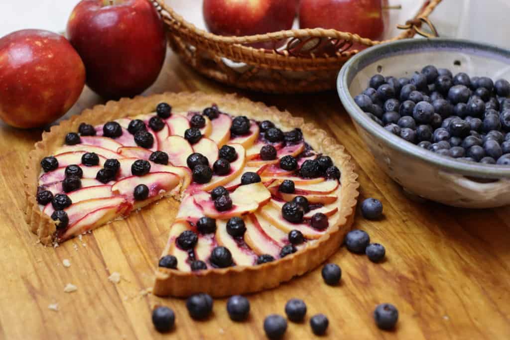 Apple Blueberry Tart with a slice cut out of it.