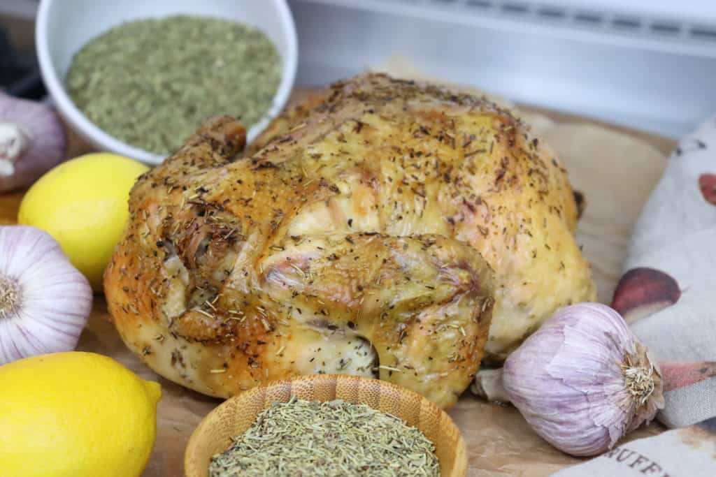 Roasted chicken surrounding by herbes de provence lemons and garlic