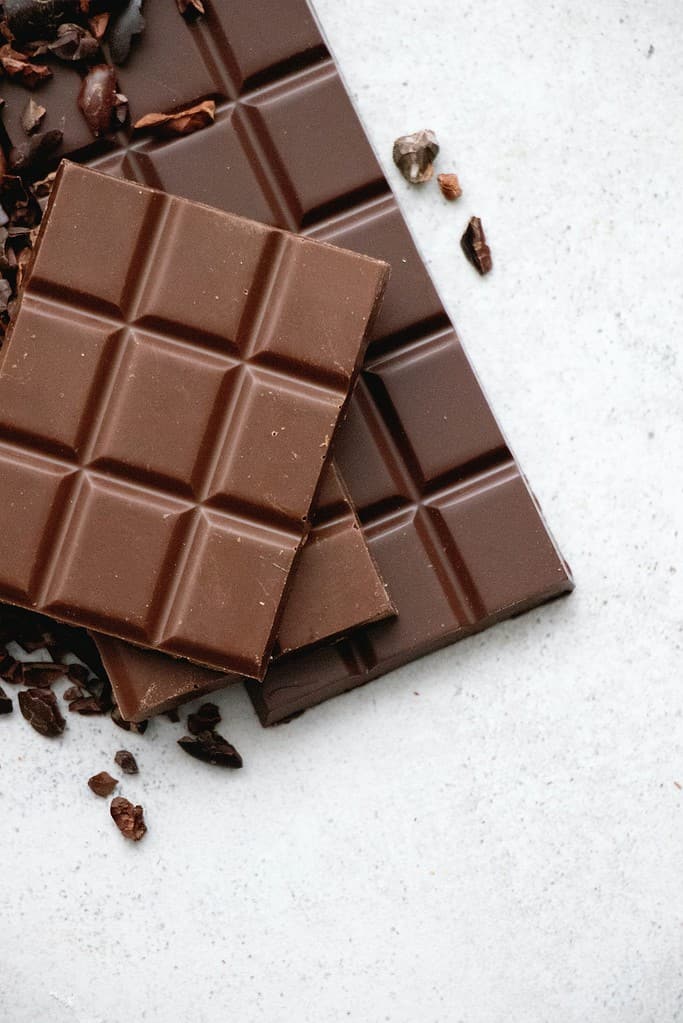 Chocolate bars with pieces on stone surface