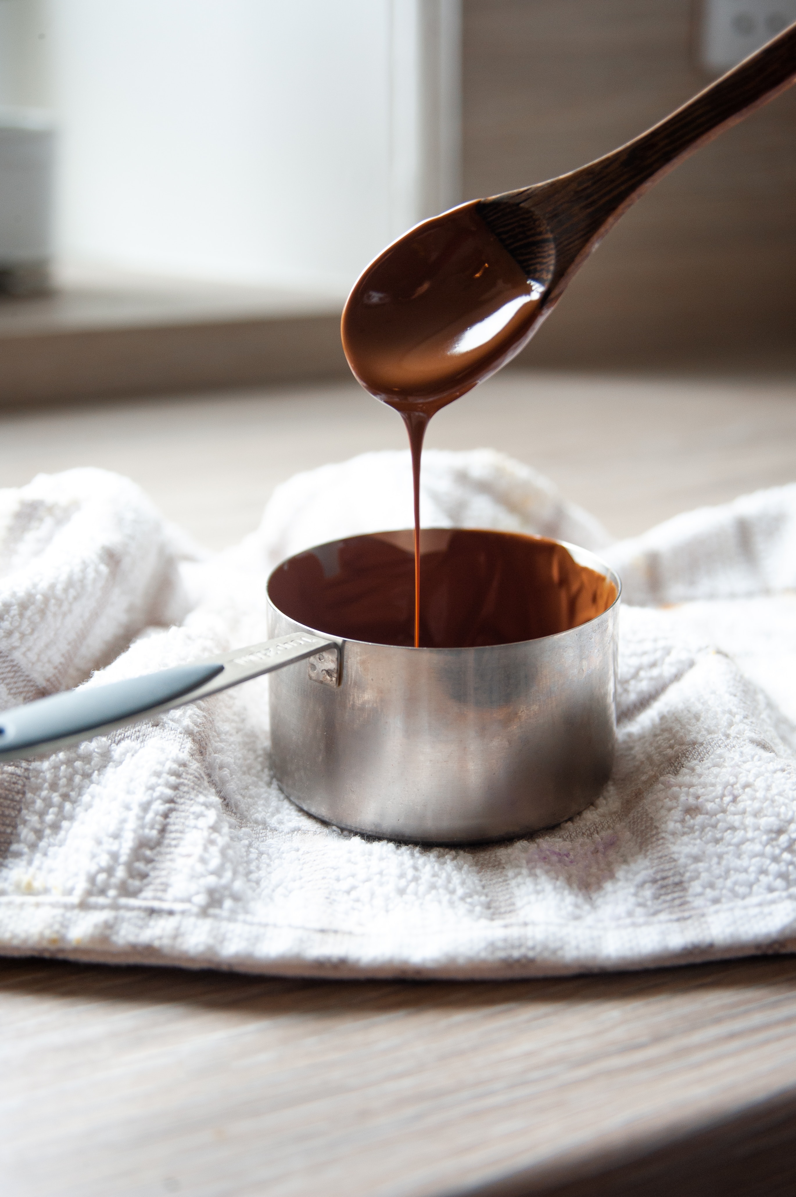 Melted chocolate dripping off of spoon into pot