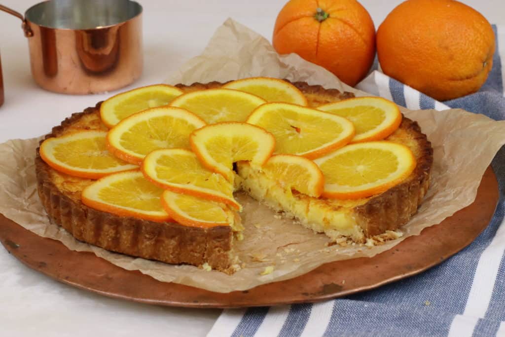 Orange tart with slice taken out of it.