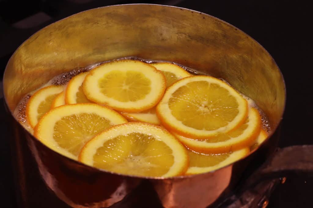 orange slices simmering in a pot of simple syrup