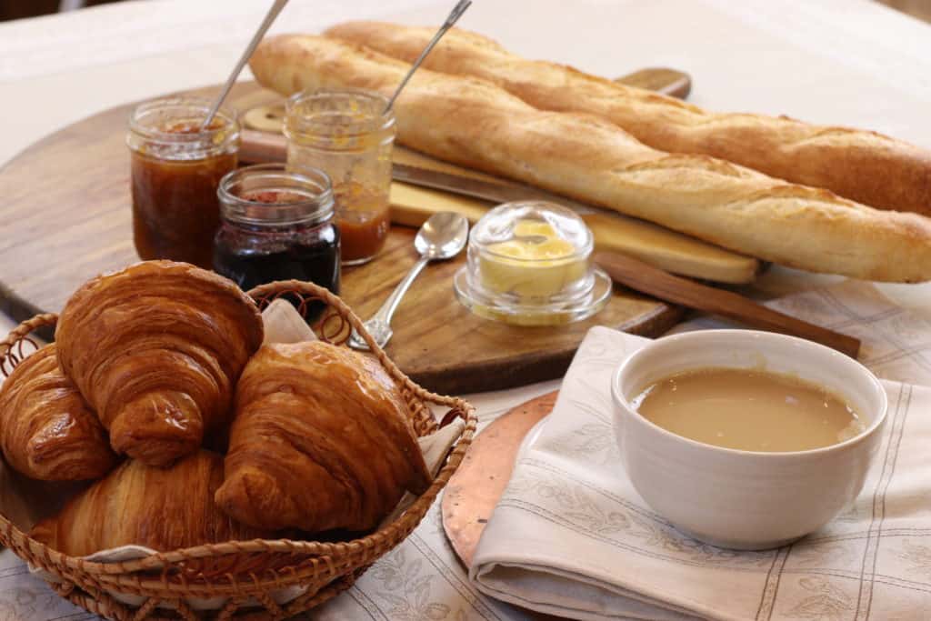 croissant, baguette, jam, and cafe au lait on a brekfast table