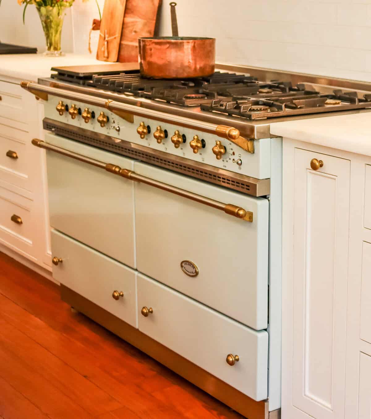 Lacanche range in a kitchen with white cabinets and wood floors