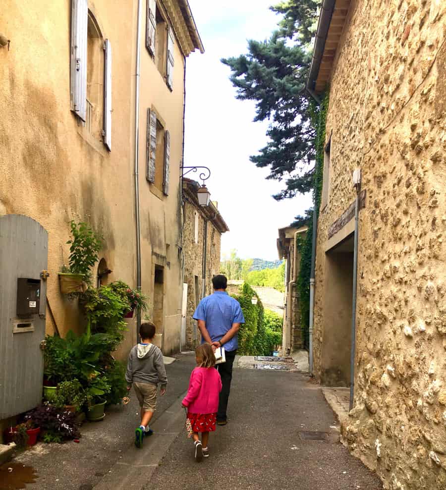 Father, son, and daughter walking down a French village street