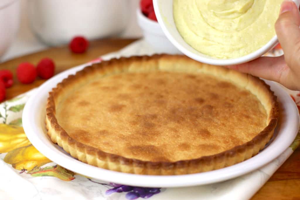 Pouring pastry cream onto a baked tart shell.