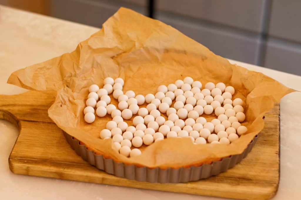 Pie weights on top of parchment paper in tart pan