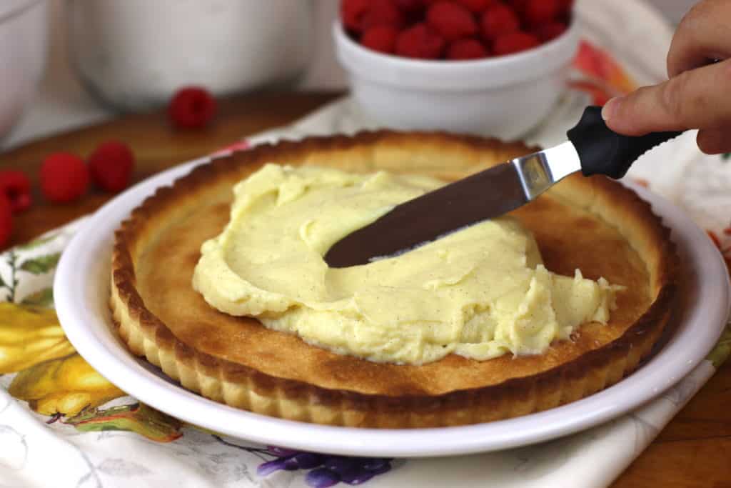 Hand spreading pastry cream in a tart shell