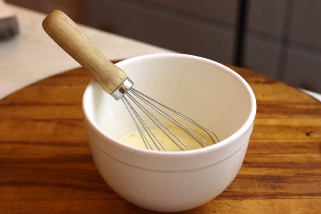 Small white bowl with wisk inside.