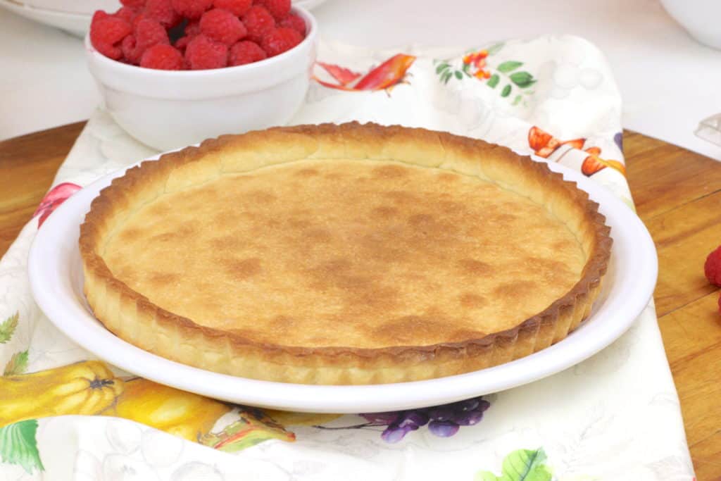 Empty tart case next to a bowl of raspberries