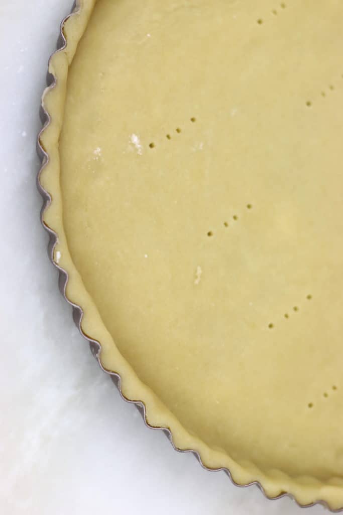 Close up of a section of unbaked tart crust in a tin