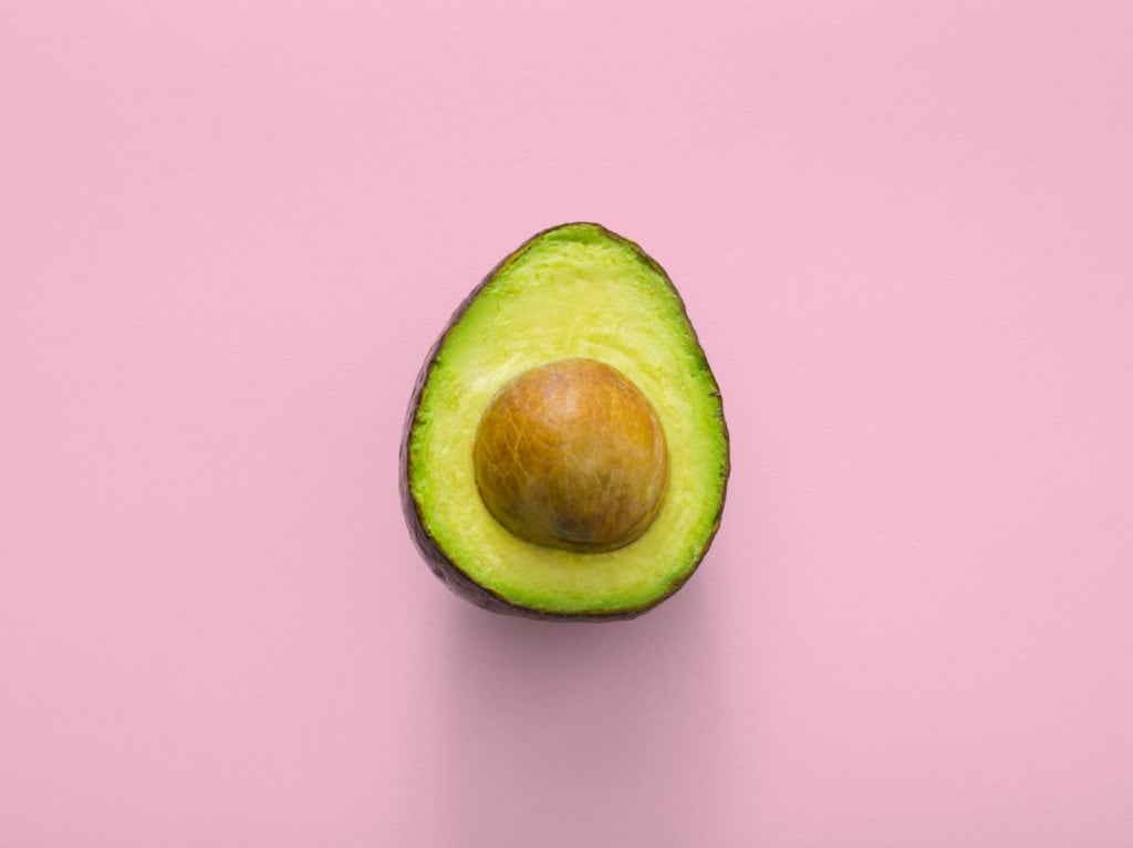 Halved avocado on a pink background