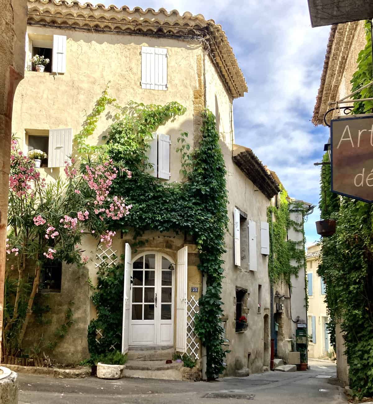 A Provencal home with pink flowers growing above a white door