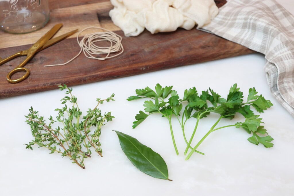 Thyme, parsley and bay leaf next to cutting board.