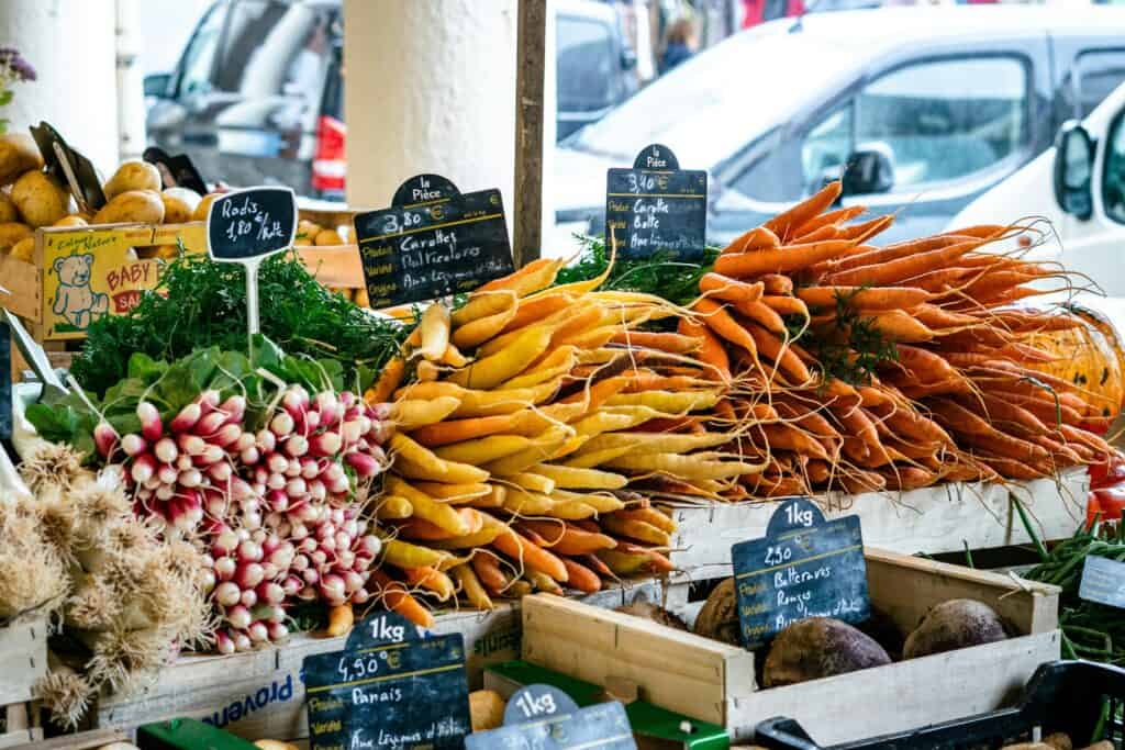 Fresh organic carrots, radishes, and beets at a French farmers market in Provence, showcasing vibrant local produce perfect for a rustic, authentic French lifestyle.