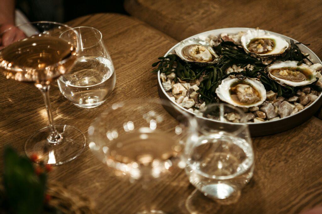 Fresh oysters on a bed of ice in a rustic setting, paired with glasses of white wine, creating a cozy and elegant French-inspired dining experience.