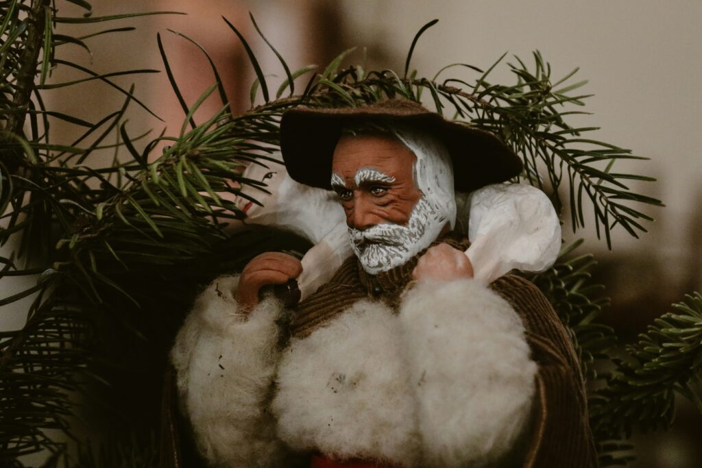 Vintage Santon figurine surrounded by pine branches, showcasing classic Christmas decorations with a rustic, French-inspired charm.
