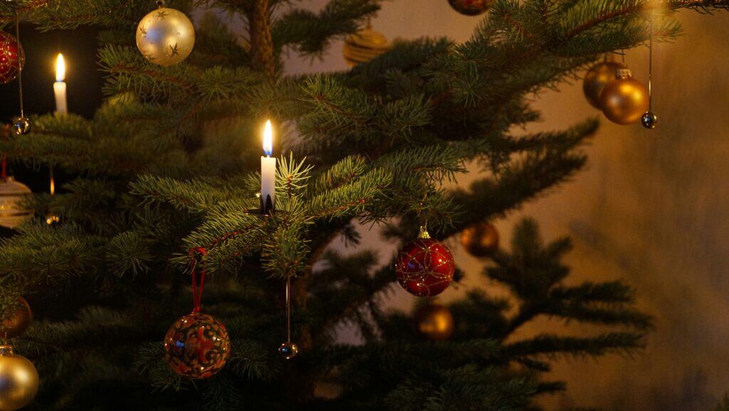 Softly lit Christmas tree with elegant gold, red, and silver ornaments, creating a cozy and festive holiday atmosphere in a charming French-inspired setting.