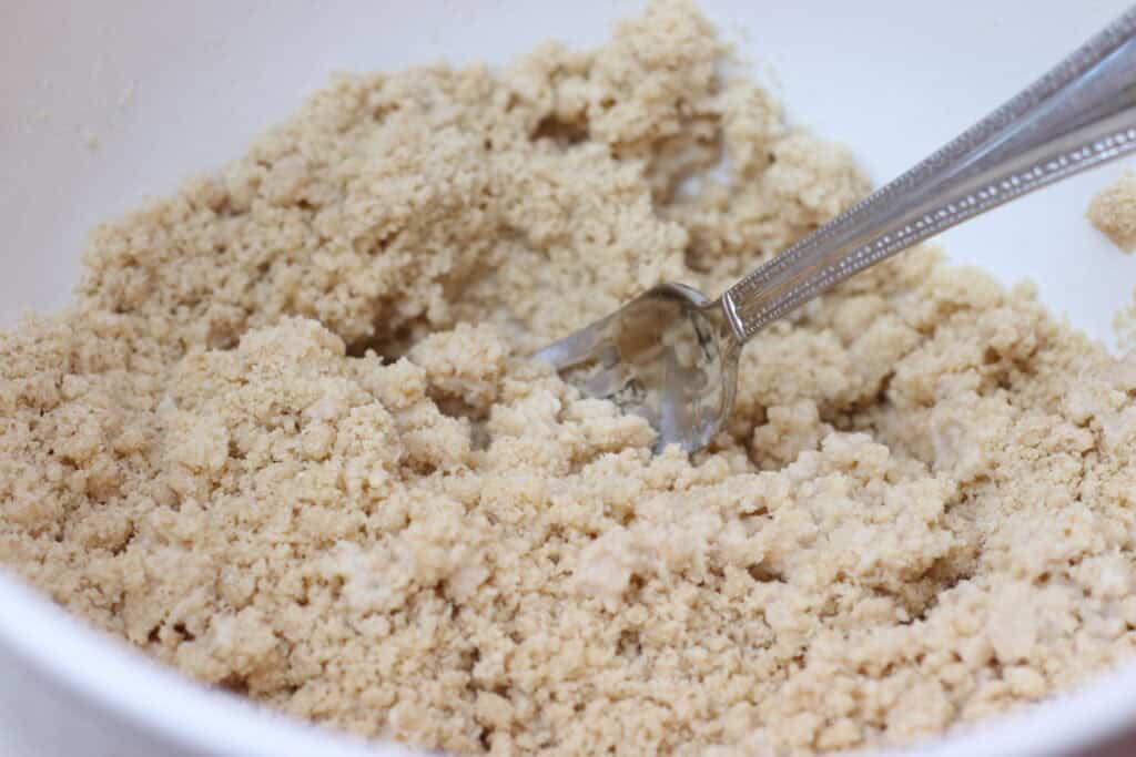 Crumbly galette crust ingredients in a white mixing bowl with a metal spoon, ideal for French desserts, pastry recipes, and baking at home.