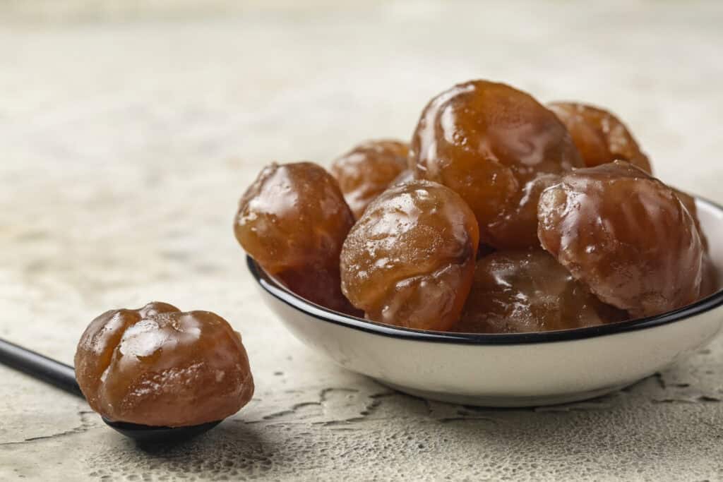 Delicious candied chestnuts in a black and white dish, perfect for French-inspired treats and dessert ideas.