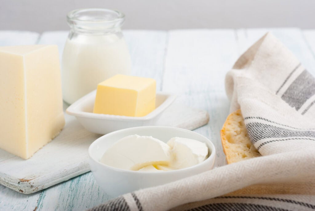 Delicious French Butter and dairy items with butter, milk, and fresh baguette on rustic white table. Perfect for French living, and gourmet food.