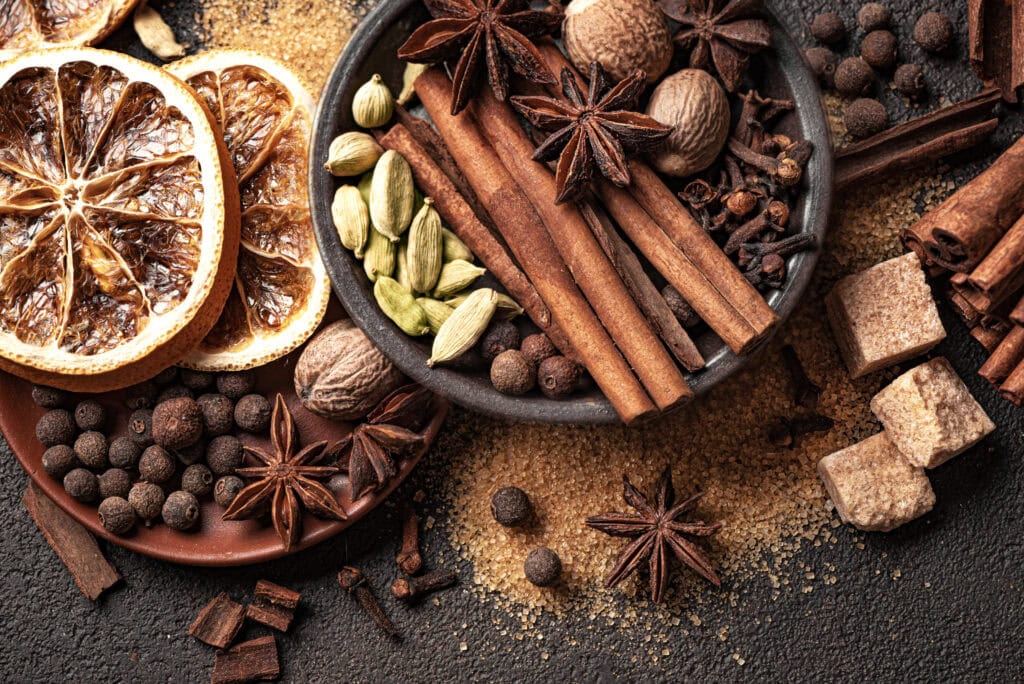 Rich mixture of dried herbs and spices including cinnamon sticks, star anise, cardamom, and dried citrus slices for authentic French flavors.