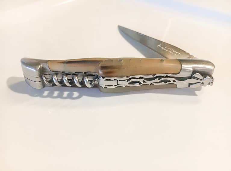 A side view of a half folded Laguiole pocket knife.