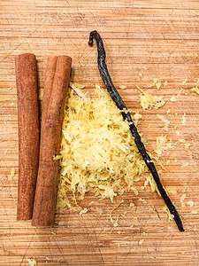 Cinnamon sticks, lemon zest, and vanilla bean on a chopping board.