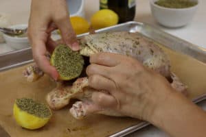 Hand inserting lemon into the cavity of the chicken.