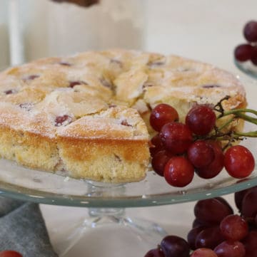 Grape cake on cake stand with a cluster of grapes adjacent