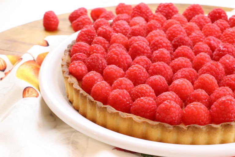 Raspberry tart on a plate sitting on a table