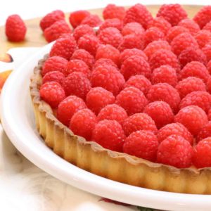 Raspberry tart on a plate sitting on a table