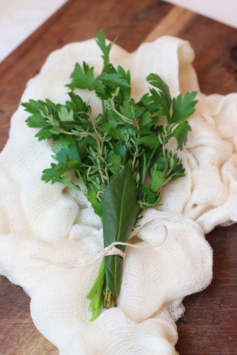 Fresh herbs including parsley and bay leaf on a wooden surface, perfect for French cooking and culinary use.