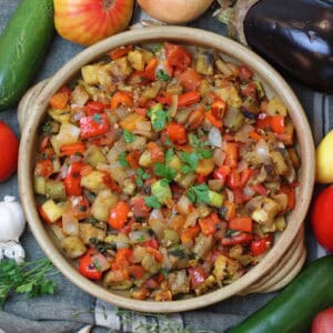 Ratatouille displayed in a rustic dish surrounded by fresh produce.