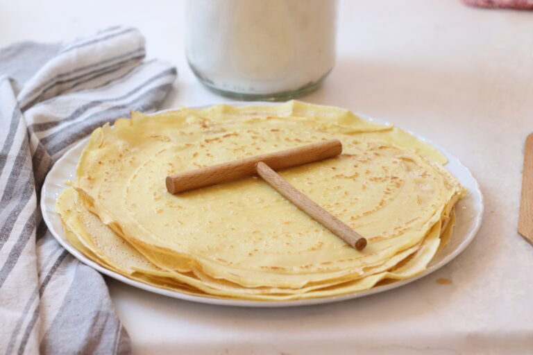 Flaky French crêpes on a white plate, ready to be enjoyed with traditional French breakfast or dessert; rustic and charming French food presentation.