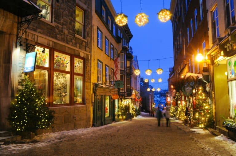 Cozy Christmas decorated street with festive lights, holiday trees, and charming historic buildings, capturing the quintessential French-inspired winter holiday scene.