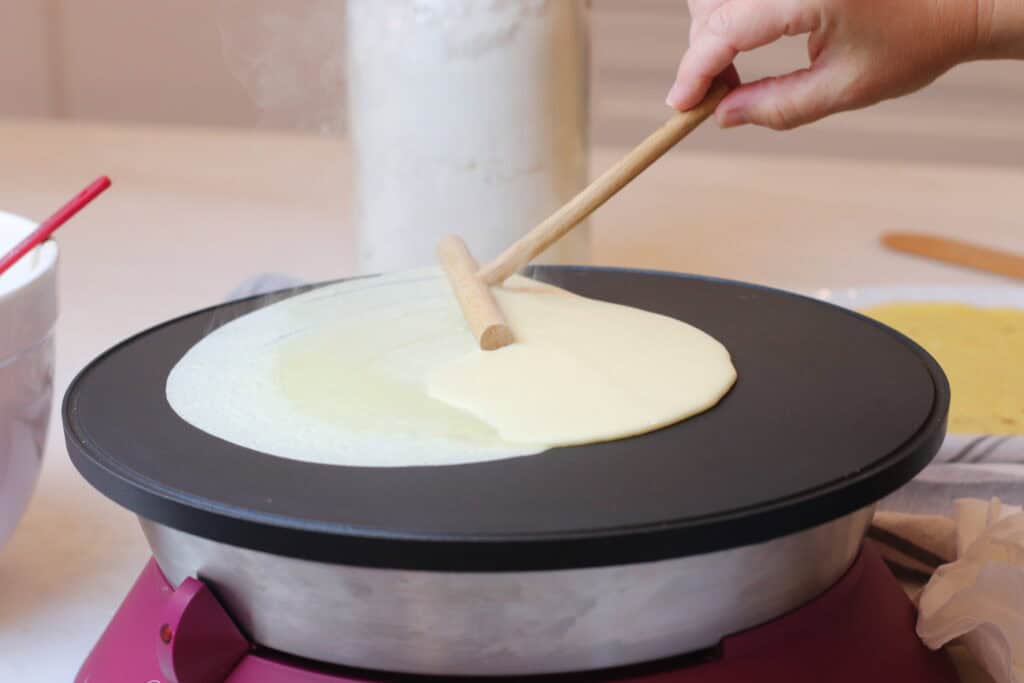 Delicious French crepes being cooked on a black skillet, showcasing a cozy, authentic French kitchen scene with steam rising.